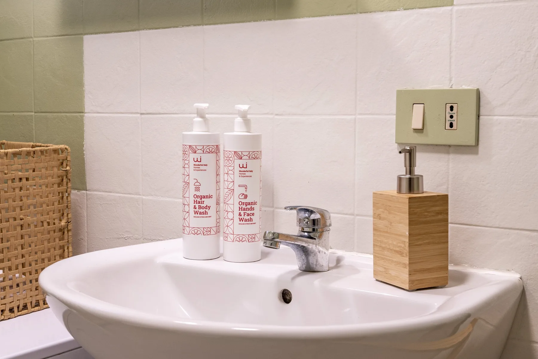 Un lavabo de baño con artículos de aseo y un dispensador de jabón de madera.