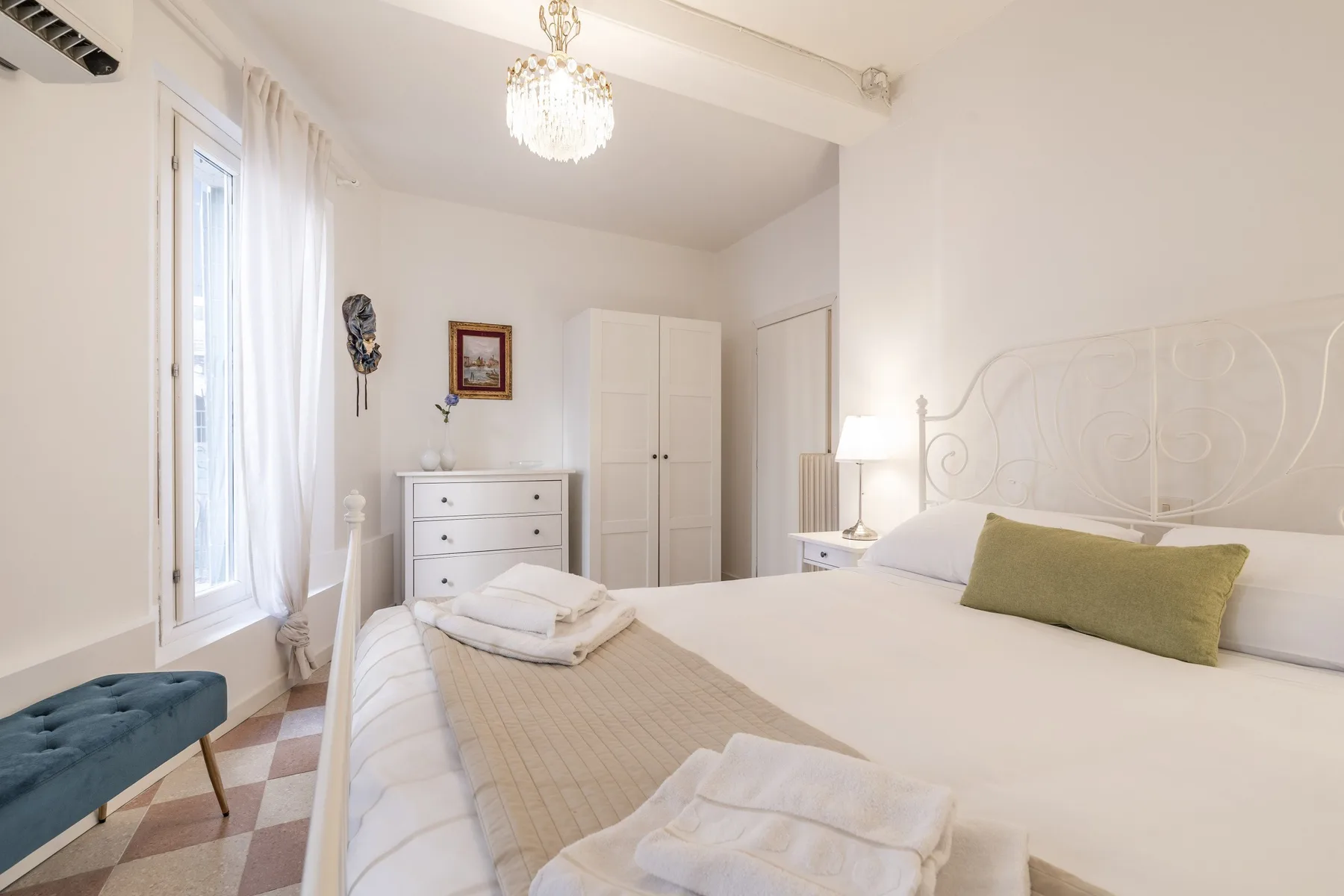 Un dormitorio luminoso con una cama bien hecha y una ventana alta.