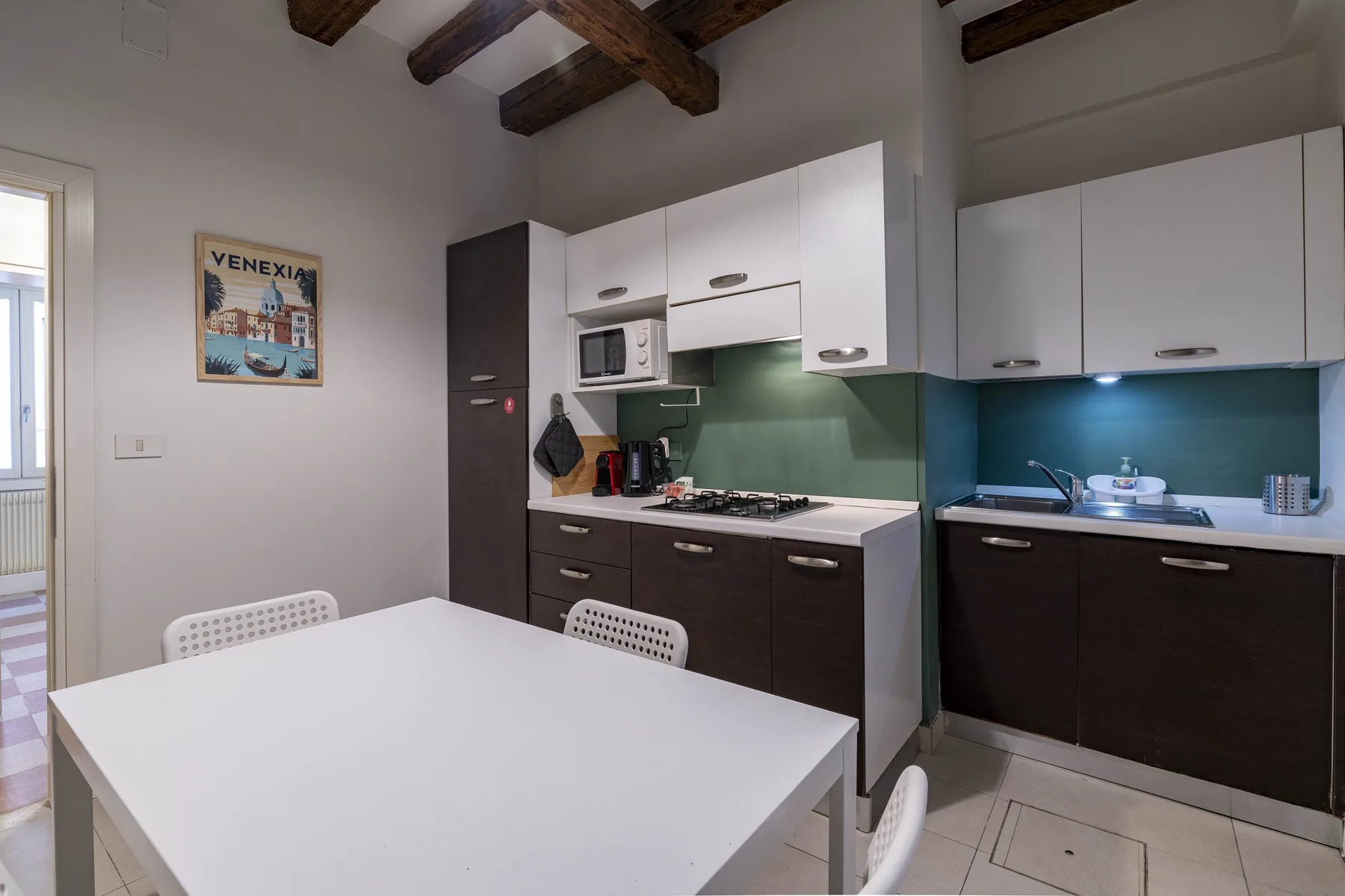 Una cocina con gabinetes oscuros, encimeras blancas y una mesa de comedor.