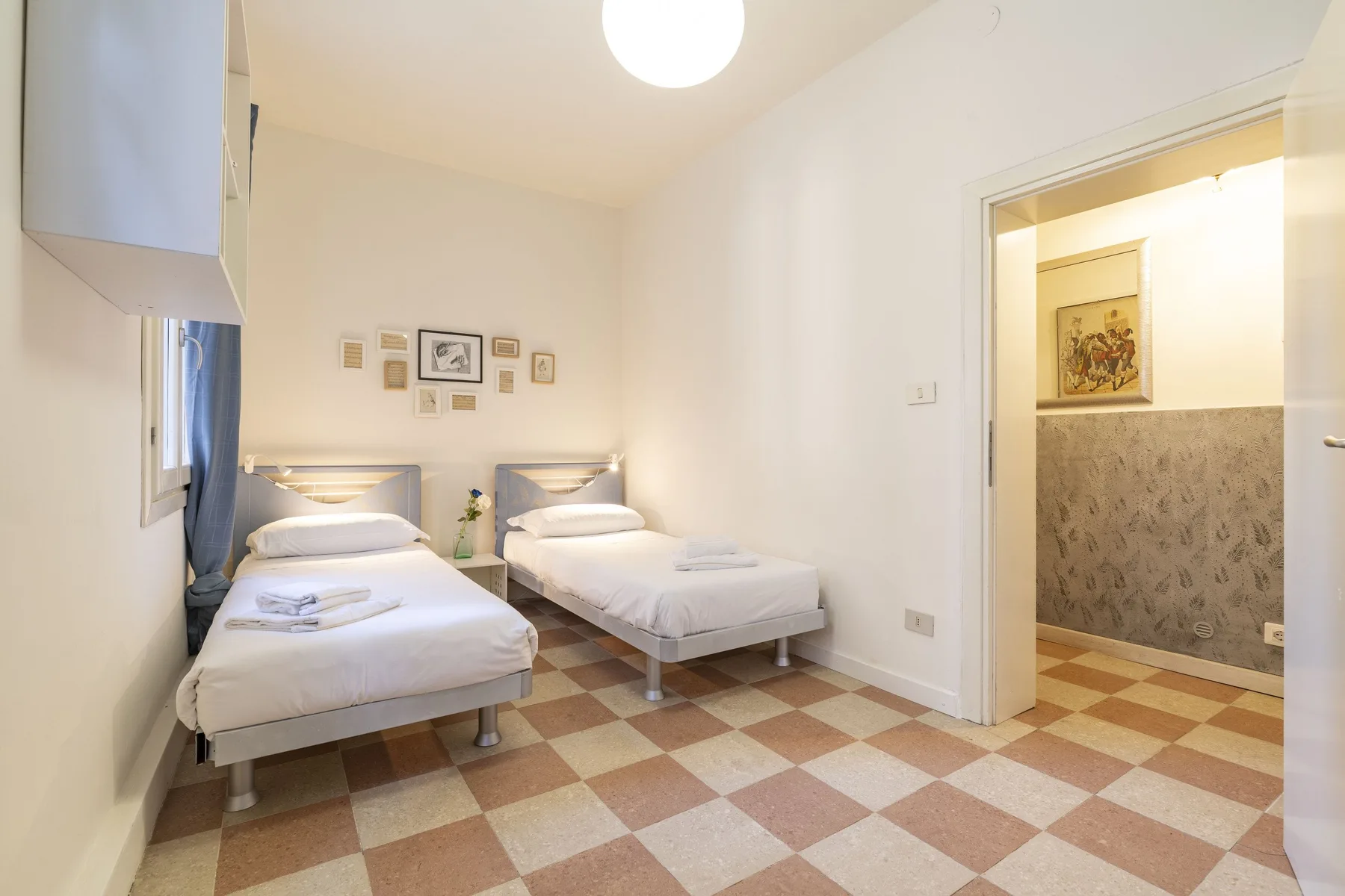 Un dormitorio con dos camas individuales y una puerta a una habitación contigua.