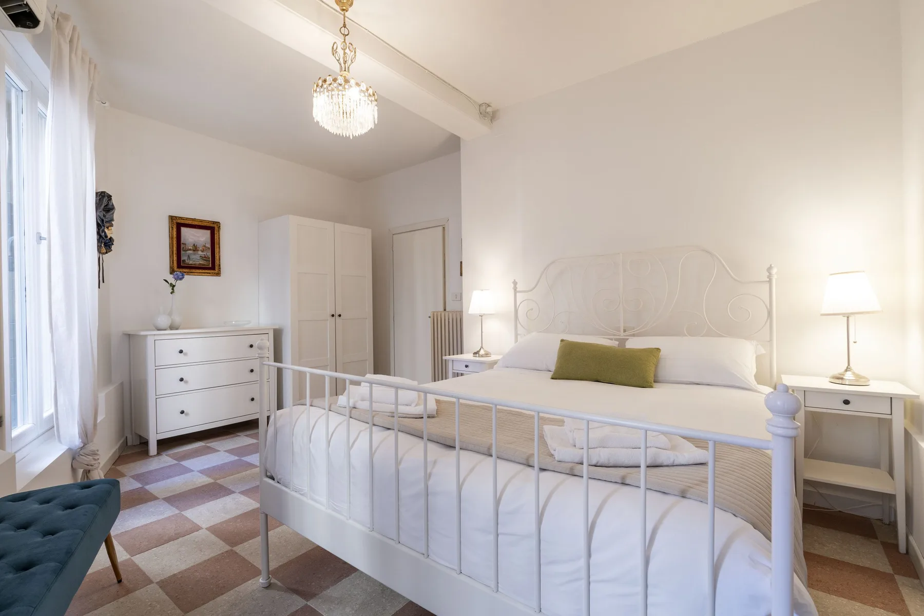 Un dormitorio luminoso con una cama blanca y mesitas de noche a juego.