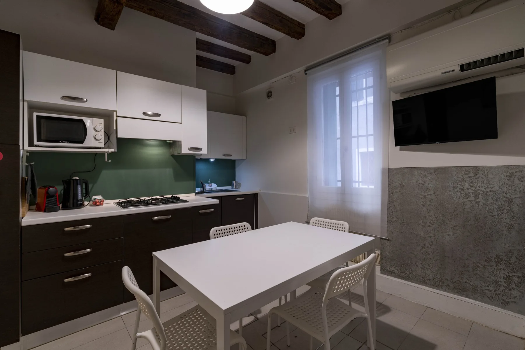 Cocina y comedor con una mesa blanca junto a una ventana.