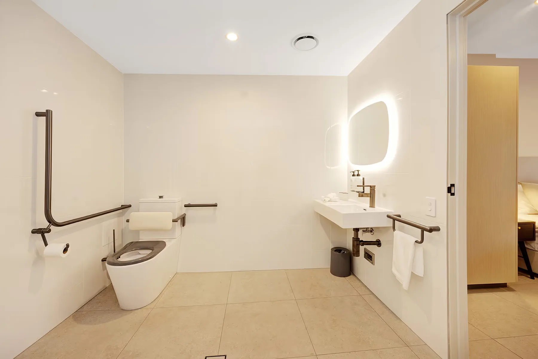 Baño accesible con barras de apoyo junto al inodoro y al lavabo.