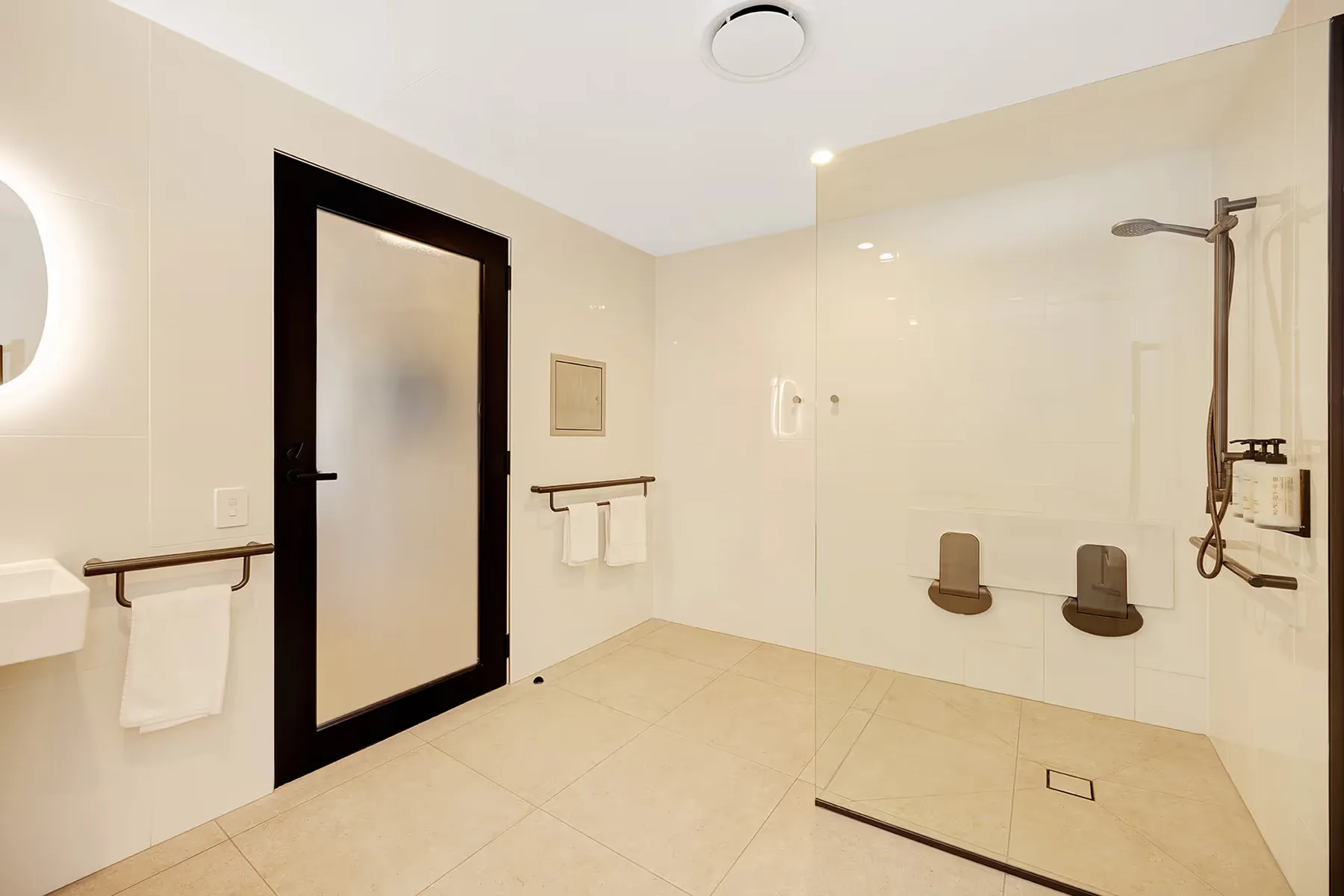Ducha con acceso para silla de ruedas y barras de apoyo en el baño accesible.