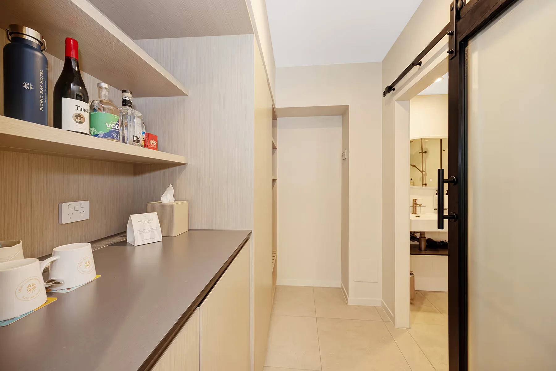 Estante del minibar y pasillo hacia el baño en la habitación Garden Queen.