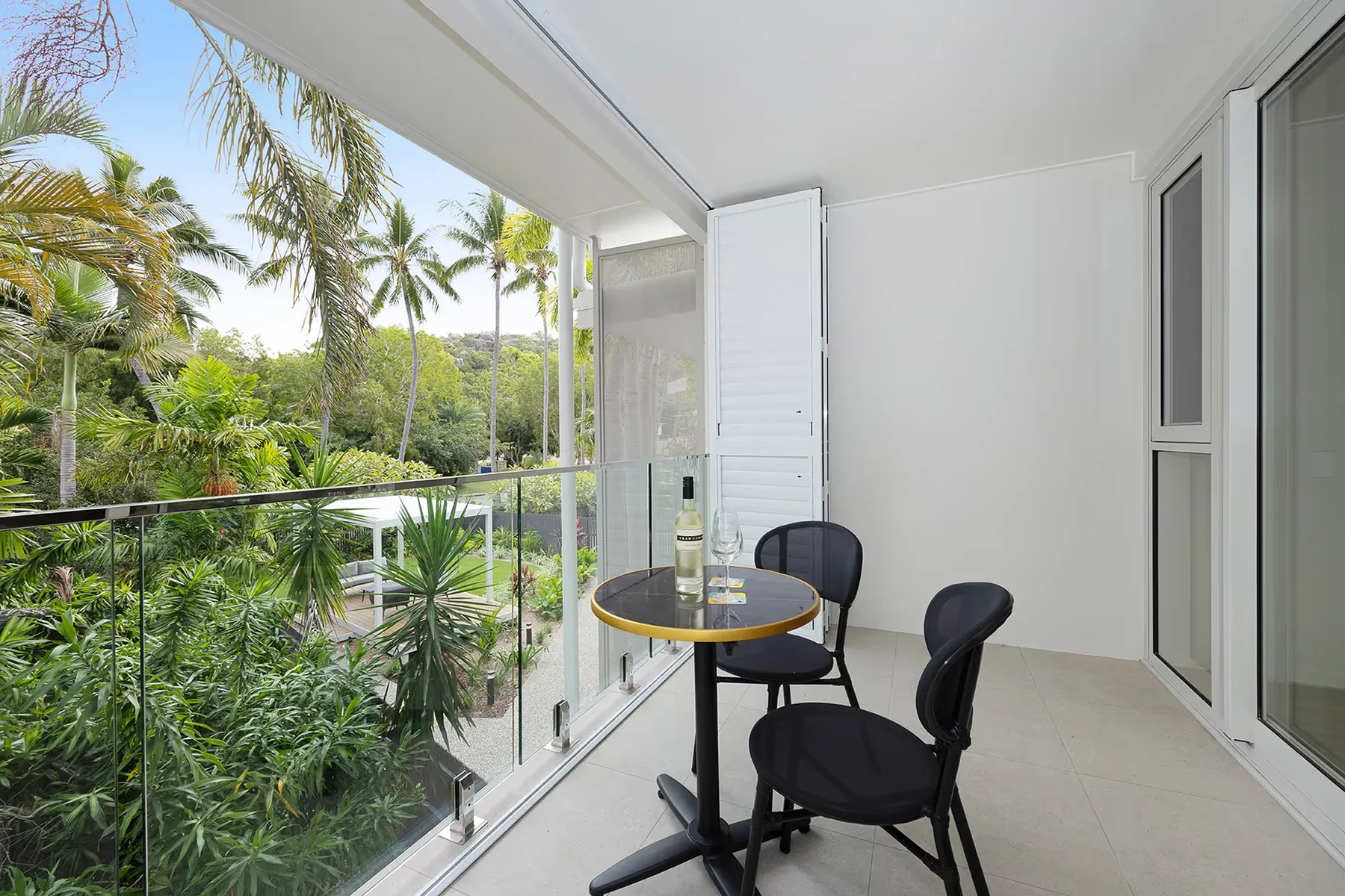 Balcón de la habitación Superior Palm con mesa y sillas entre las palmeras.