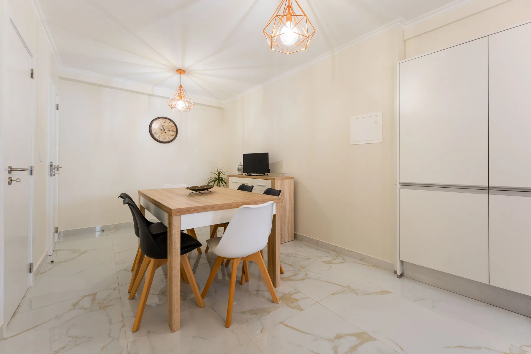 Comedor con una mesa de madera, sillas y un televisor pequeño.