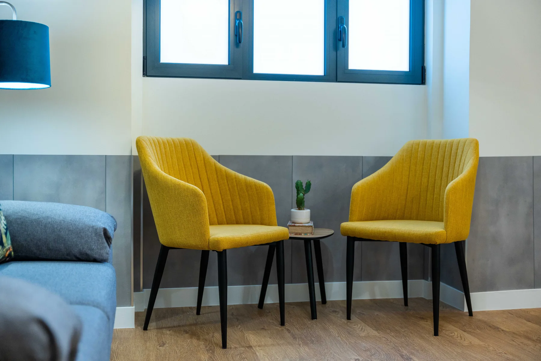 Una zona de estar con dos asientos amarillos alrededor de una mesa pequeña.
