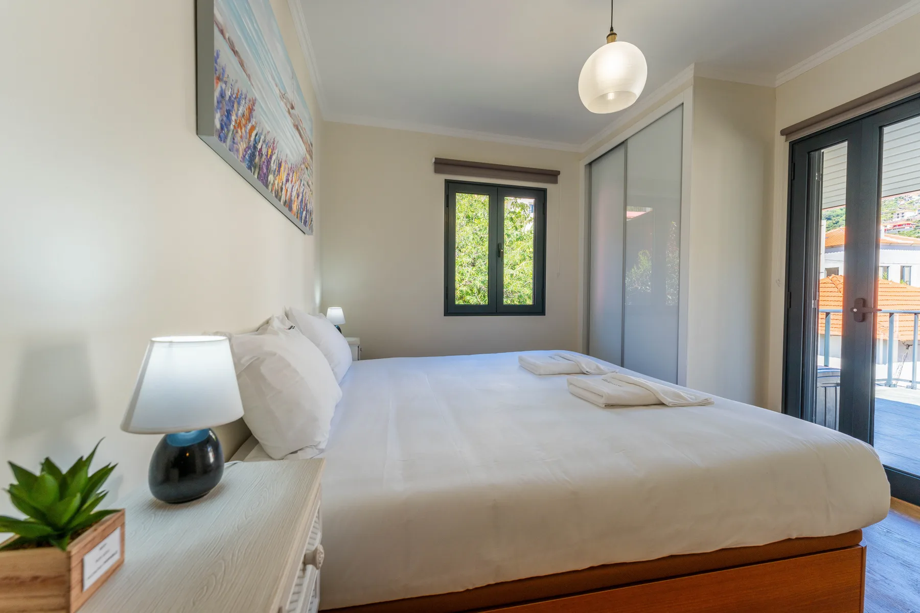 Un dormitorio luminoso con una cama grande junto a una puerta de cristal.