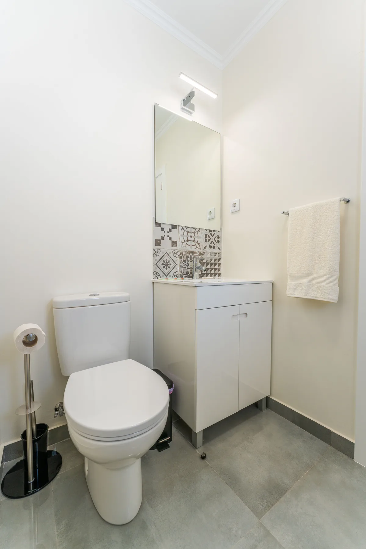 Un baño con inodoro, mueble de lavabo y espejo.