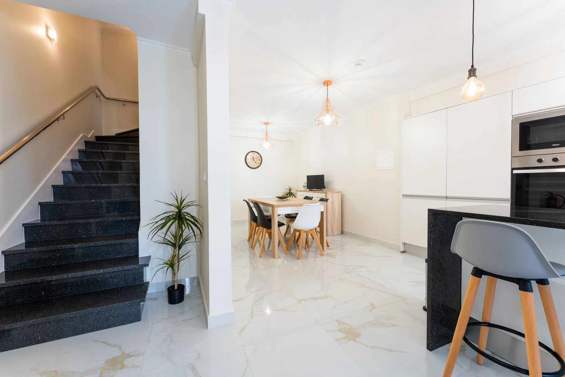 Una luminosa cocina-comedor diáfana con una escalera al lado.