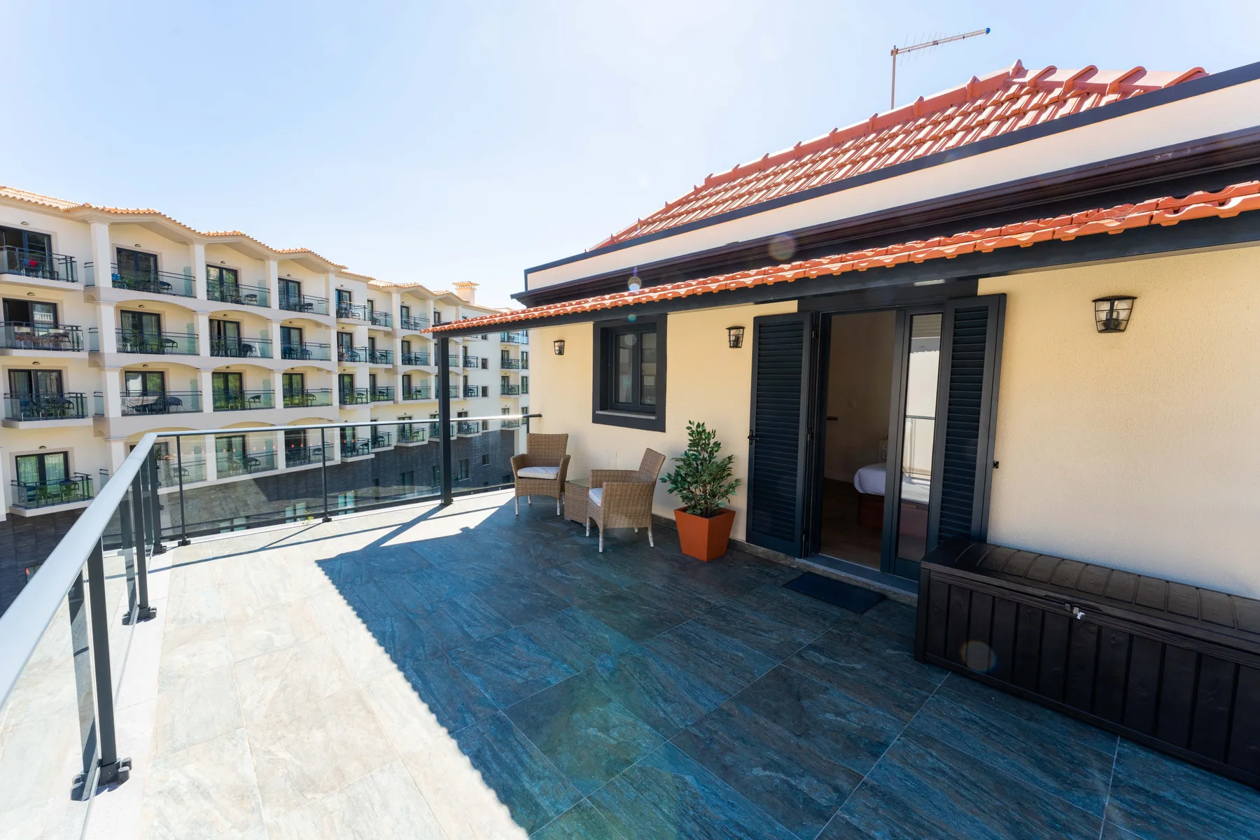 Una terraza en la azotea con asientos al aire libre y vistas a edificios de apartamentos cercanos.