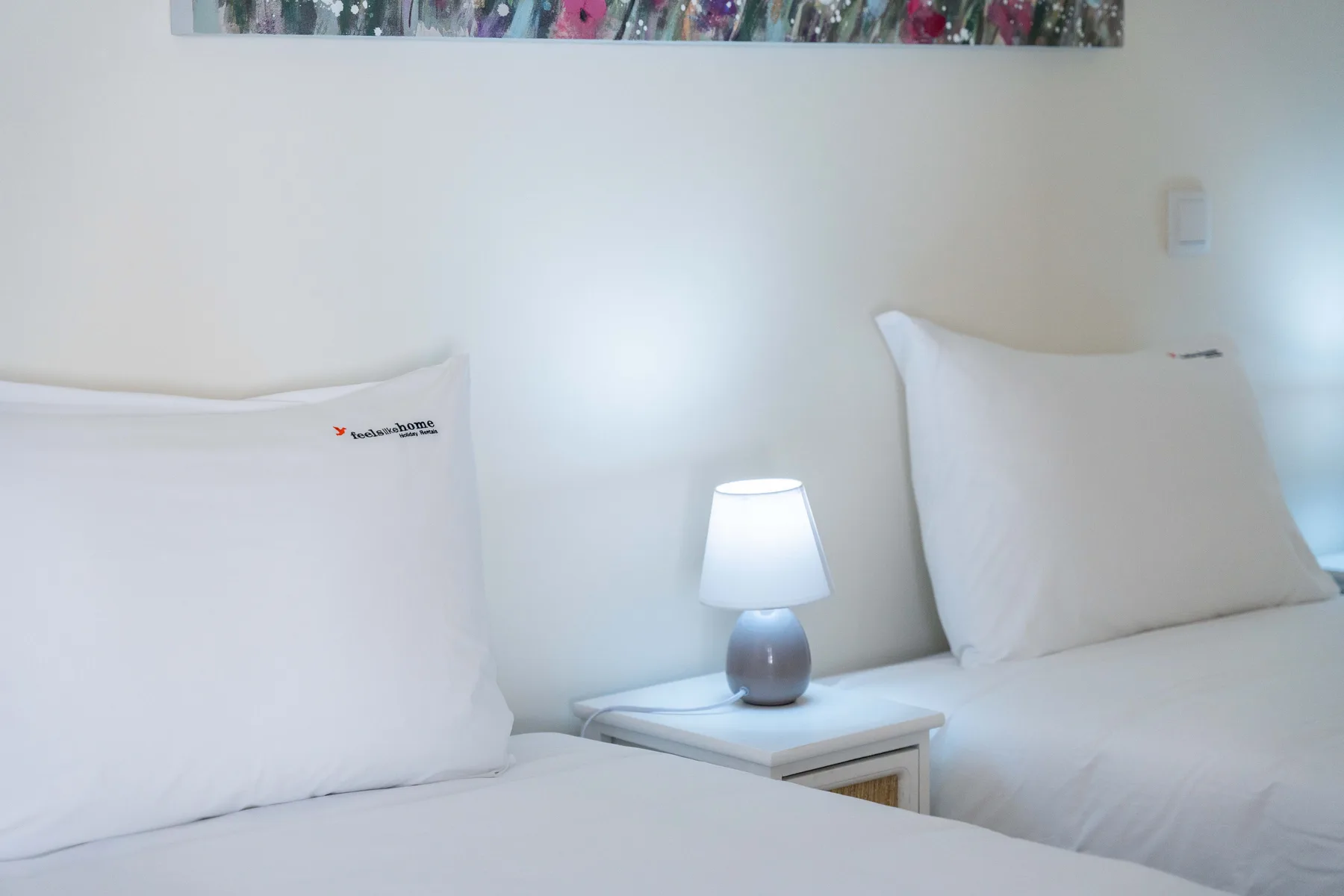 Dormitorio con dos camas y una pequeña lámpara de noche.