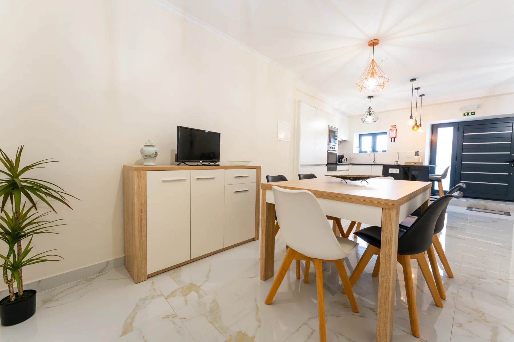 Un comedor luminoso con una mesa de madera y sillas junto a una cocina.