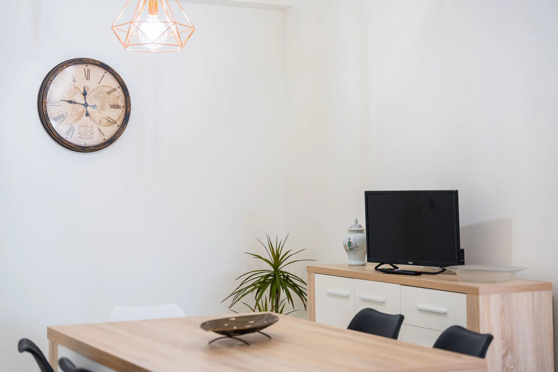 Comedor con mesa, asientos y un televisor sobre un mueble.