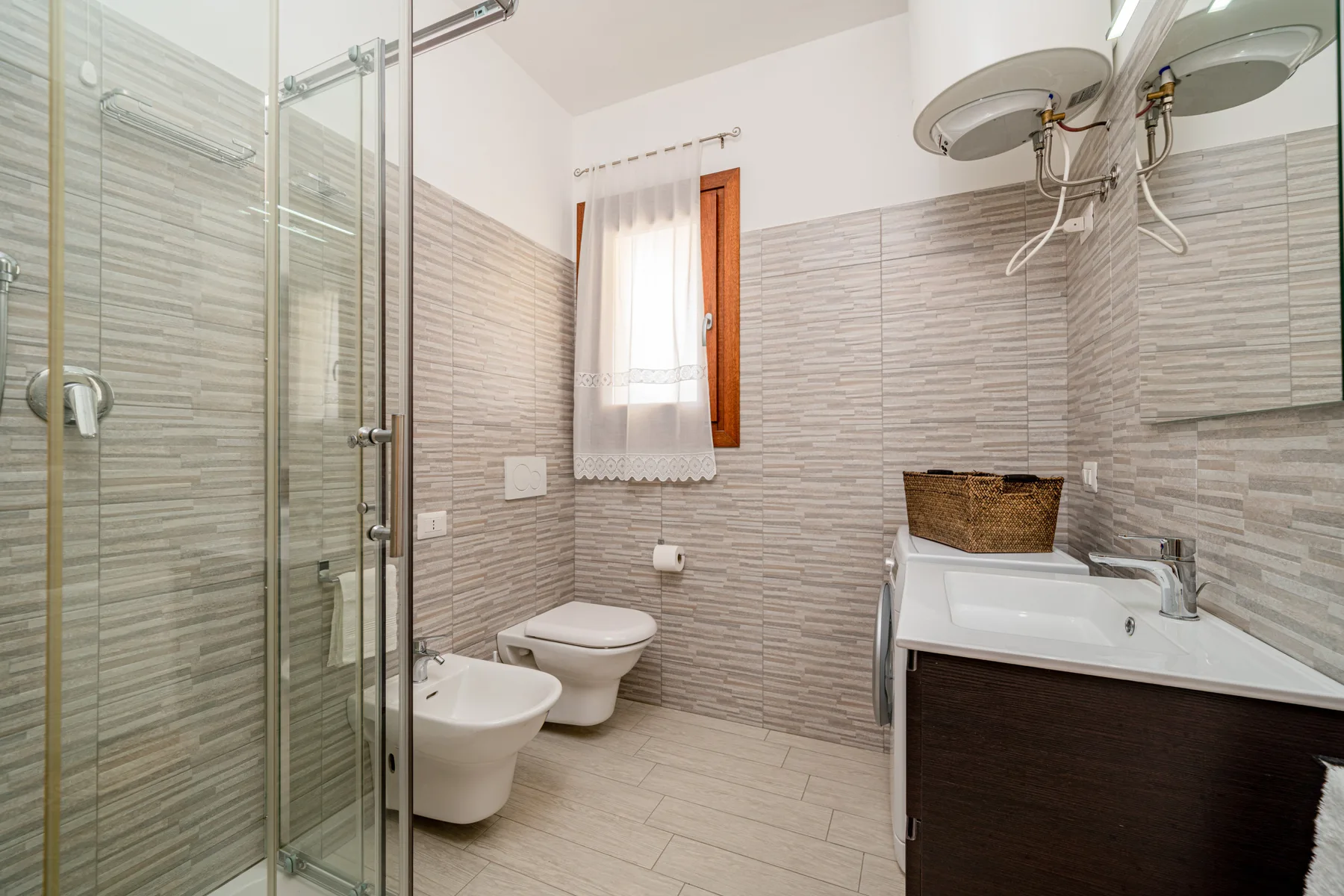 Un baño alicatado con ducha de vidrio, inodoro y lavabo.