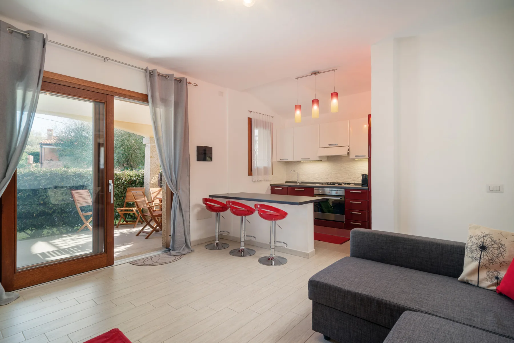 Una sala luminosa da a un patio junto a una cocina compacta.