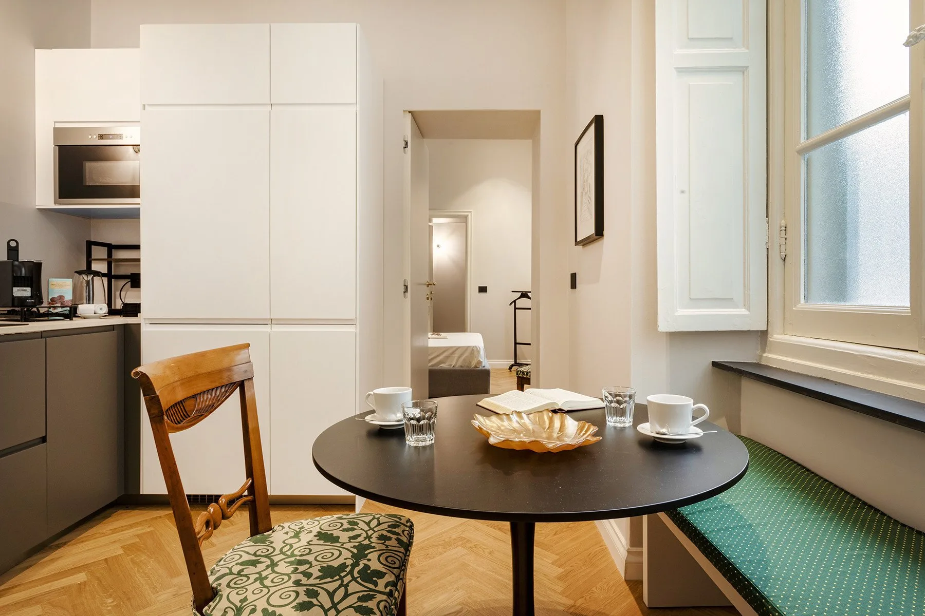 A compact kitchen and dining area with a round table beside a large window.