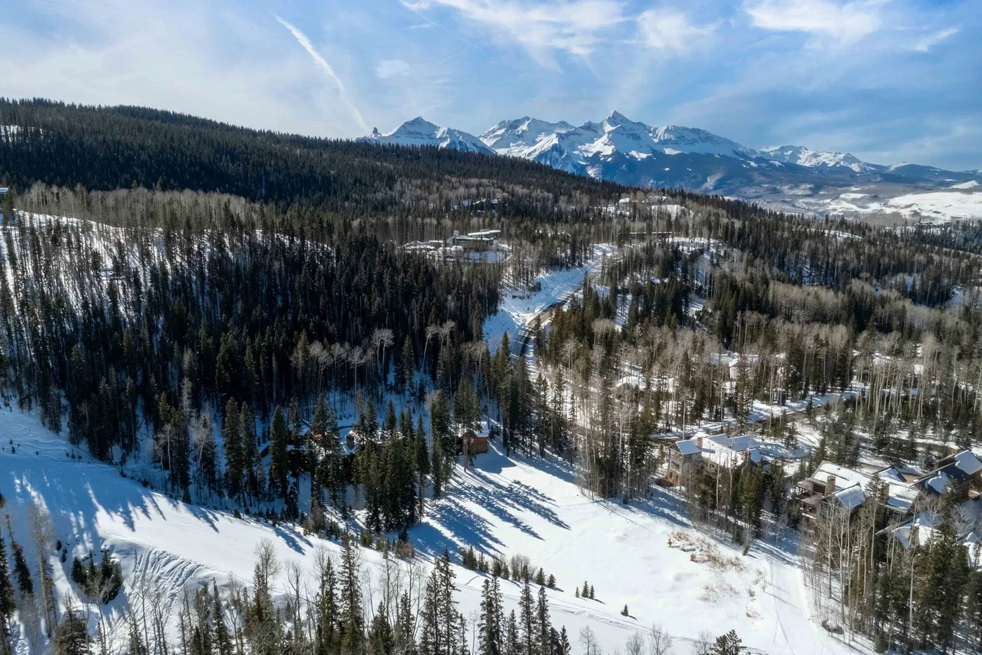 A snowy mountain landscape with forested slopes and scattered buildings.