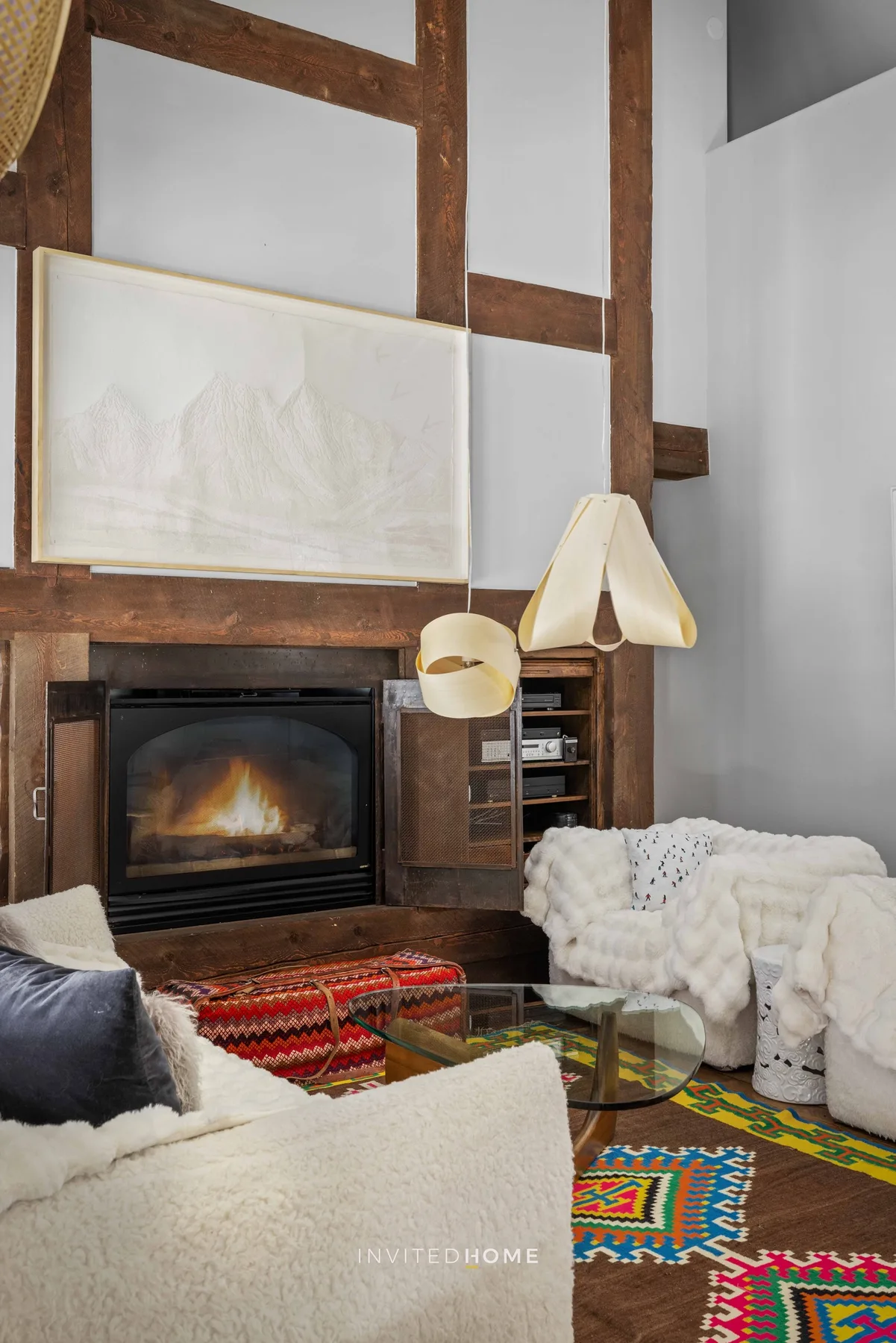 A living room with a fireplace, seating, and colorful patterned rugs.