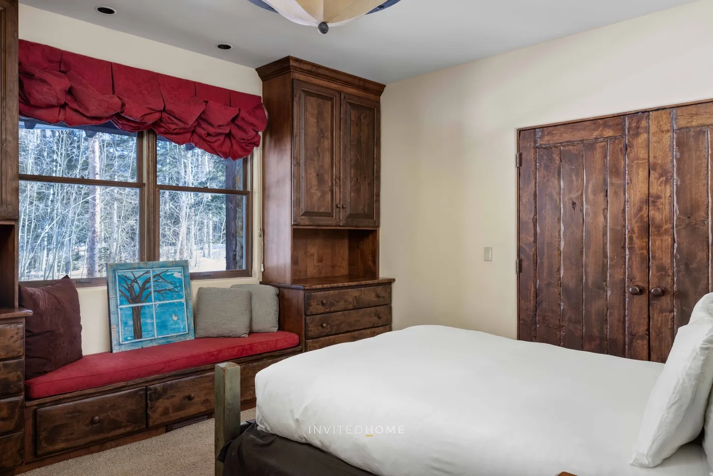 A bedroom with a bed, a window, and wooden furnishings.