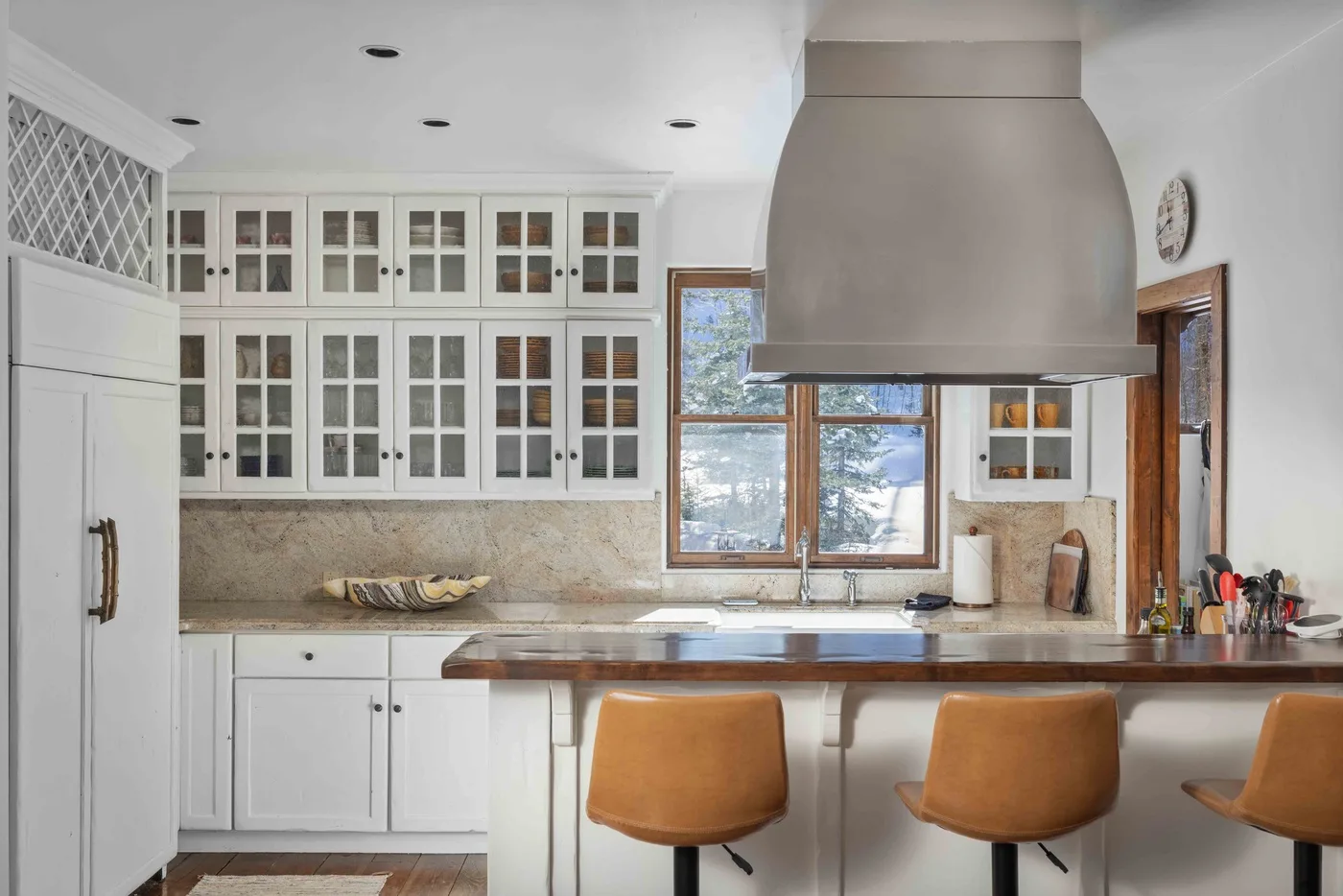 A bright kitchen with white cabinets, a central island, and windows above the counter.