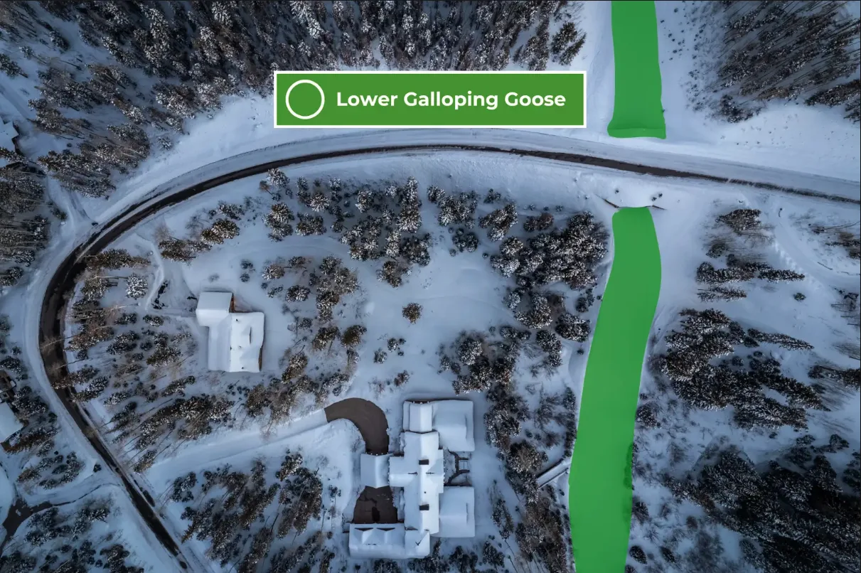 An aerial view shows a snow-covered landscape with winding roads and scattered buildings.
