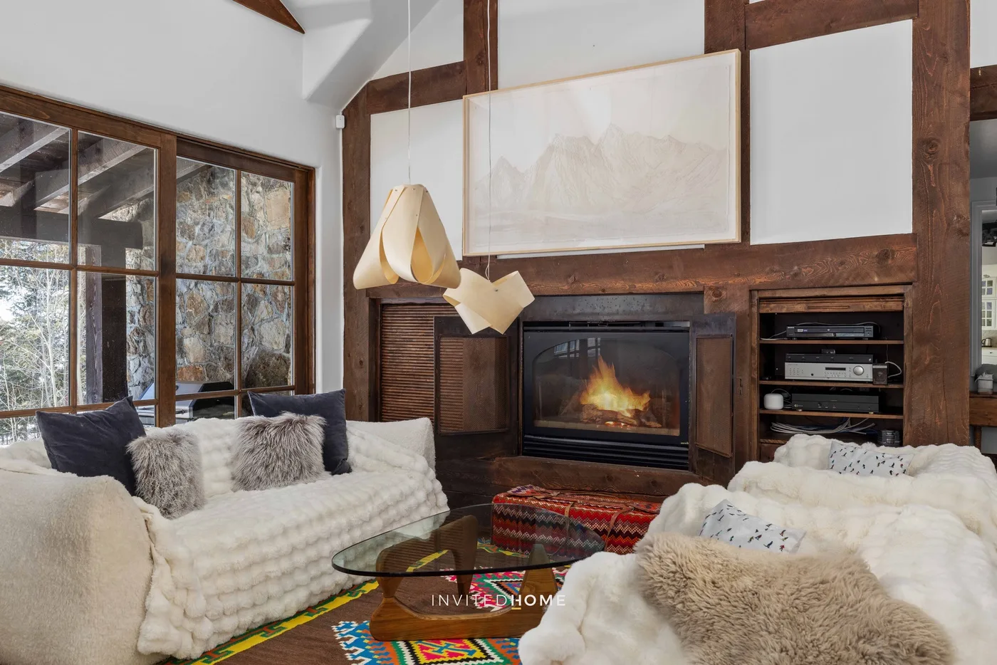 A living room with seating around a fireplace and large windows.