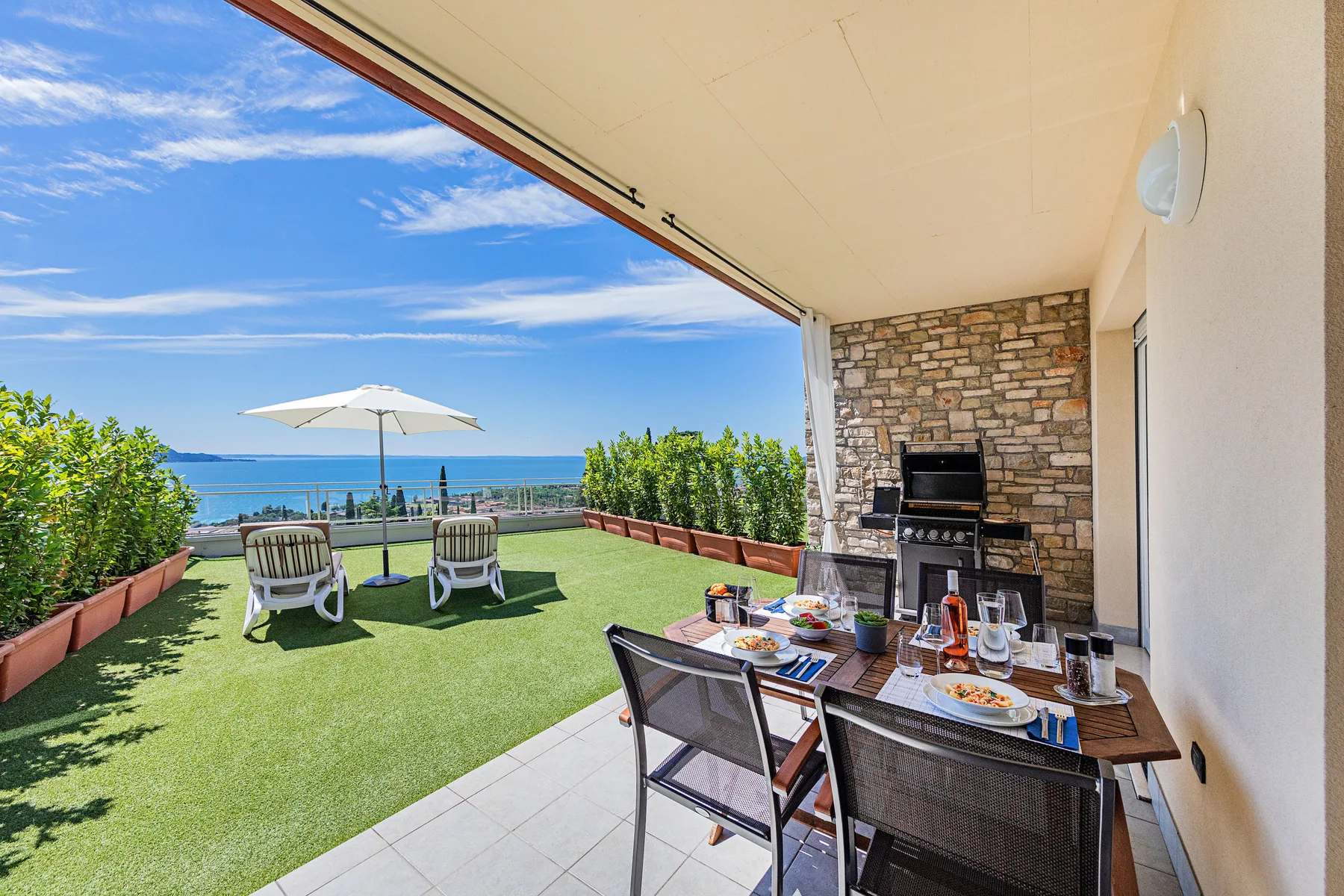 Una zona cubierta de comedor al aire libre da a una terraza con asientos y vistas al mar.
