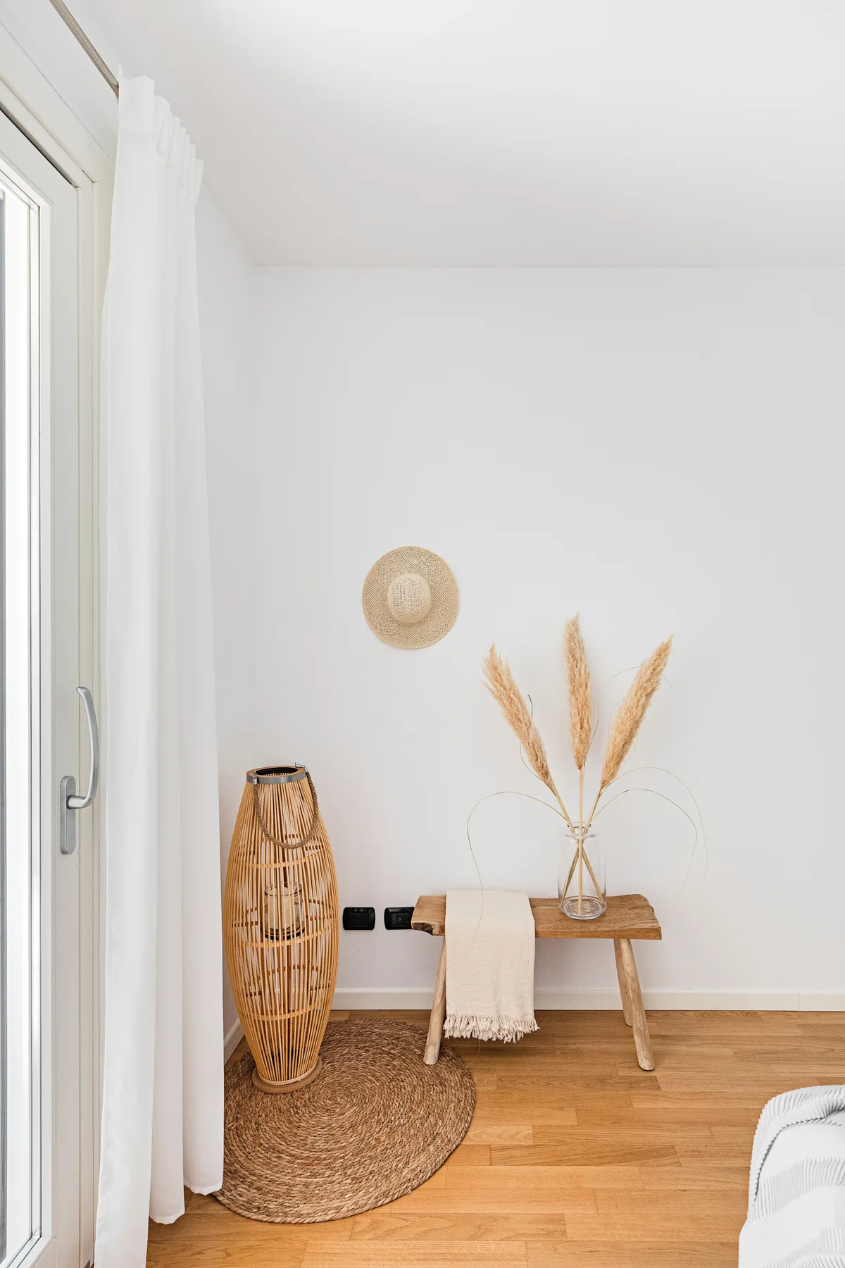 Un dormitorio luminoso con un banco bajo de madera y hierbas secas.