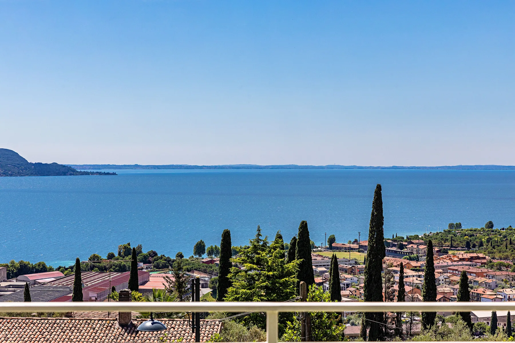Un pueblo junto al lago, con tejados y árboles, domina un amplio lago azul.