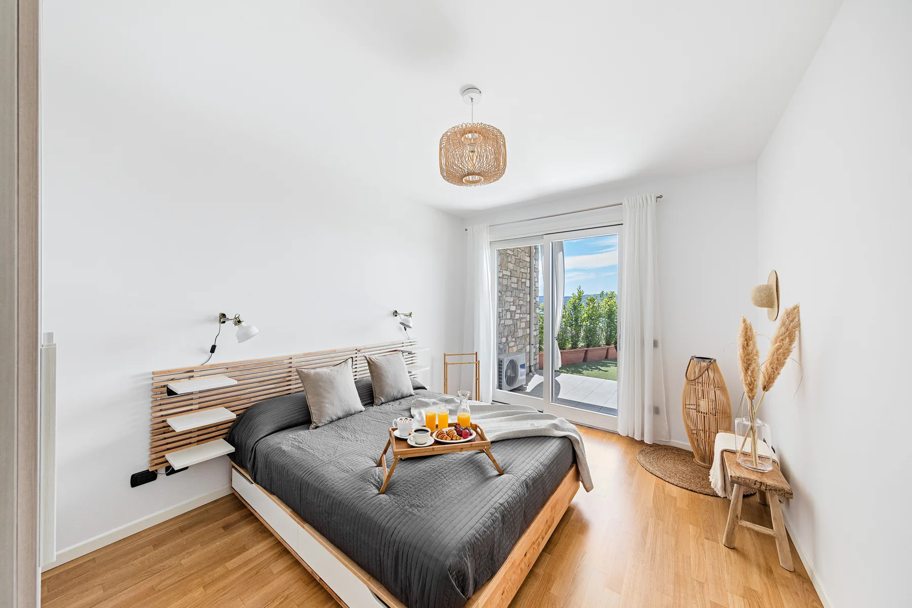 Un dormitorio luminoso con una cama frente a puertas de vidrio que dan a un balcón.