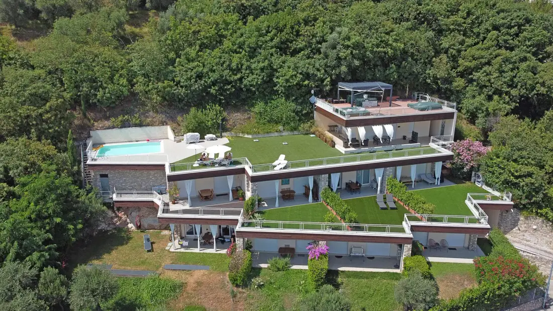 Una casa moderna de varios niveles está rodeada de árboles frondosos.
