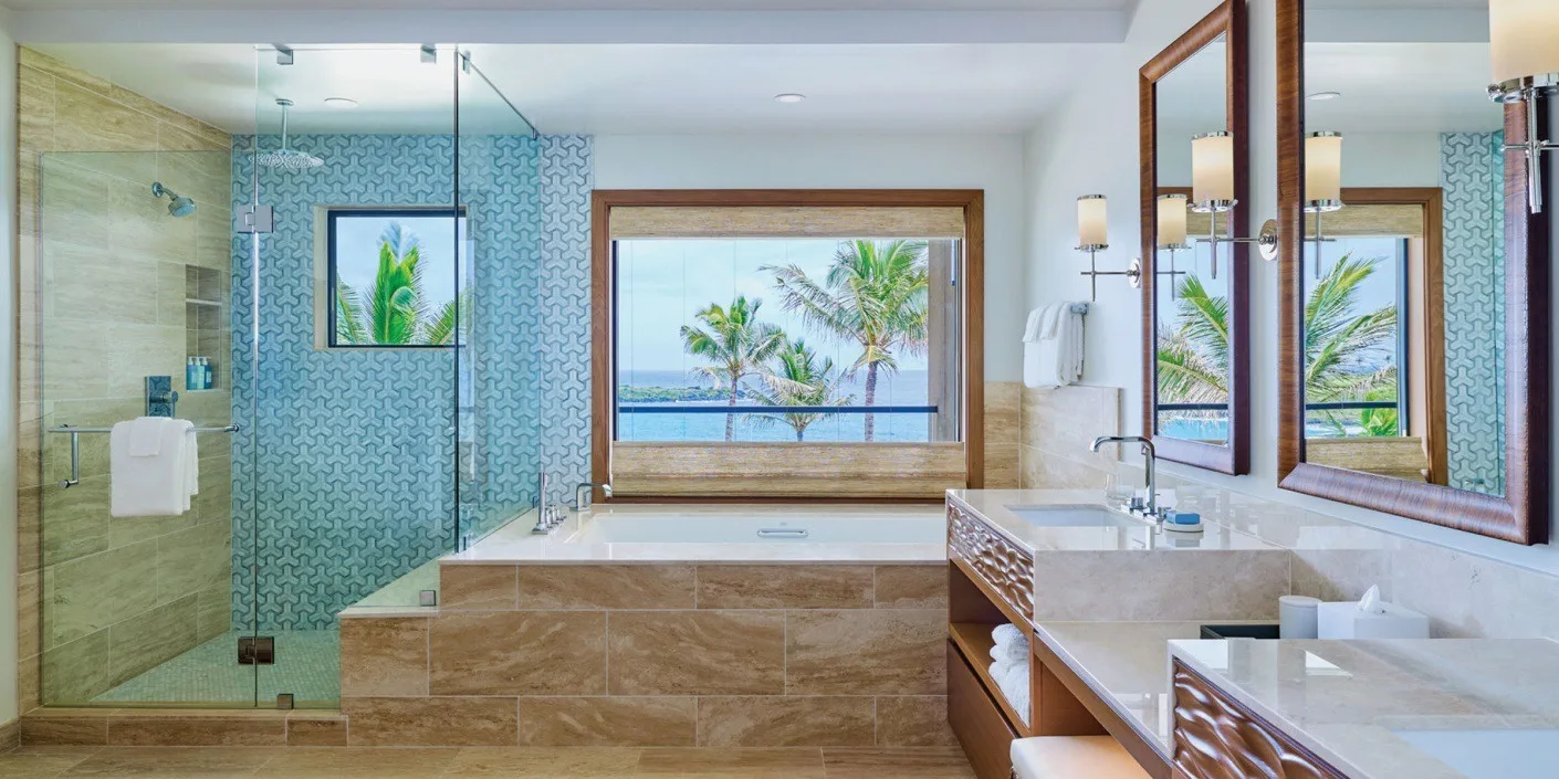 Un baño luminoso con ducha de cristal y una ventana amplia con vistas a palmeras.