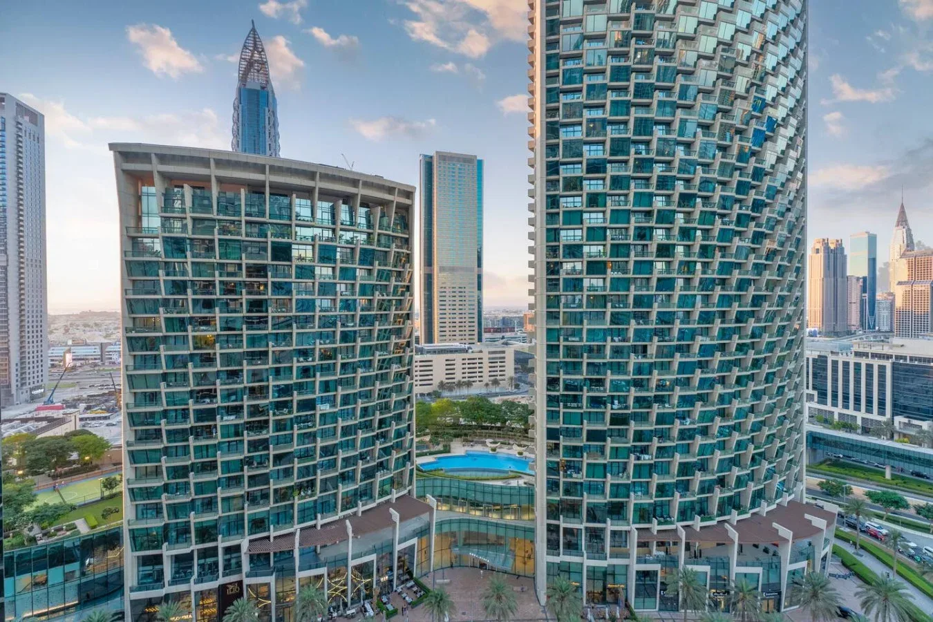 Cityscape with two modern high-rise buildings and a blue pool below.