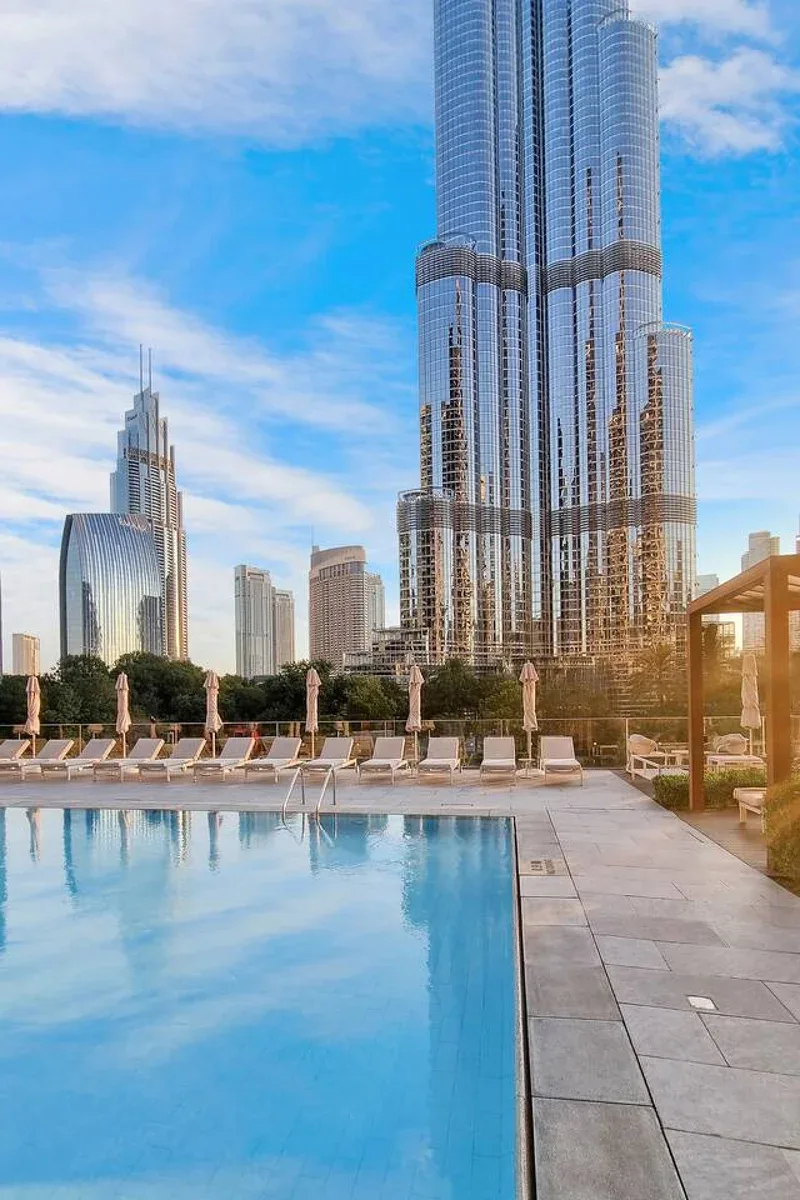 A rooftop pool and deck overlook a cluster of tall city skyscrapers.