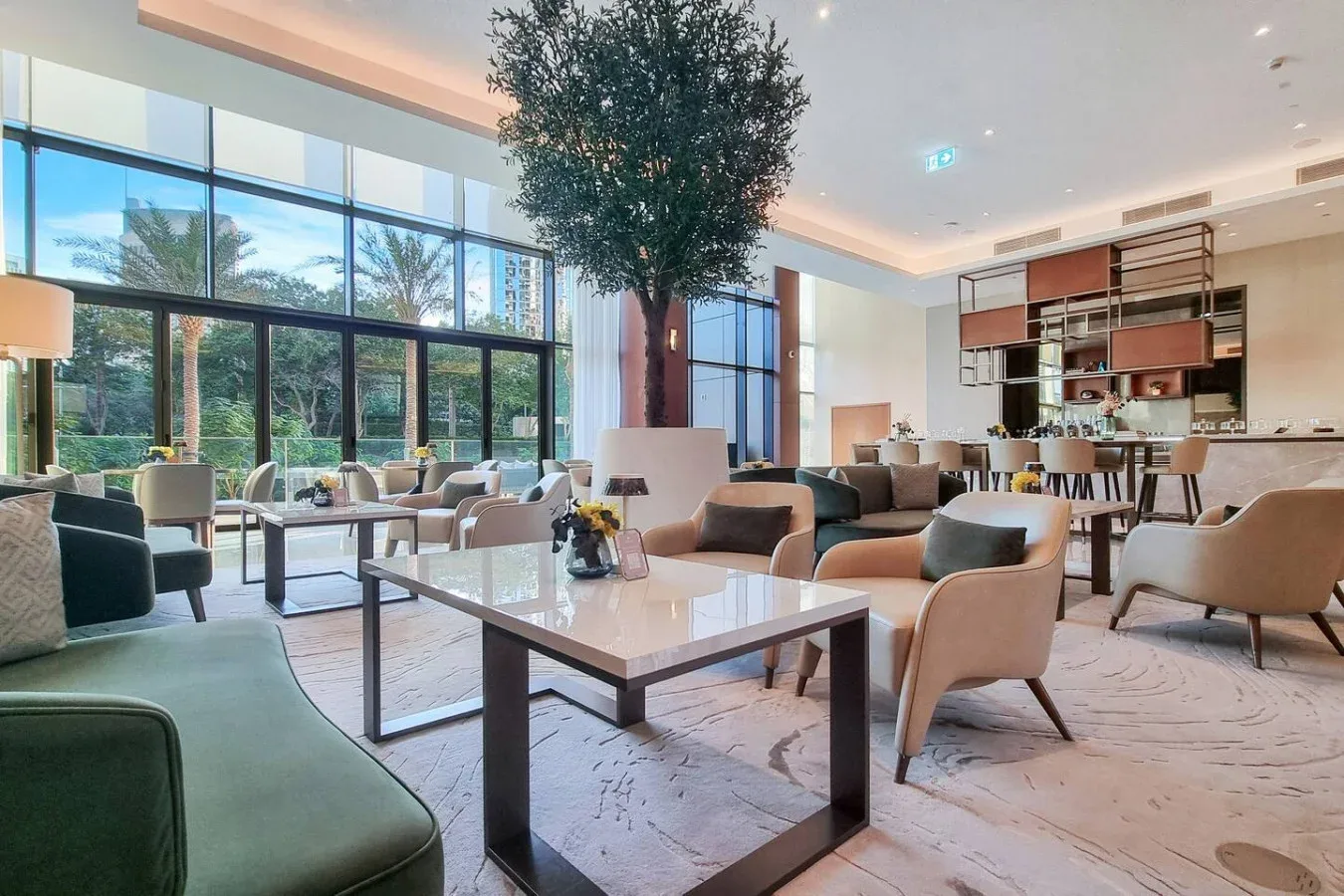 A spacious lounge with seating around low tables and large windows.