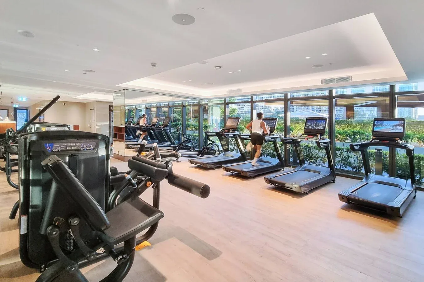 A fitness room with treadmills and other exercise equipment beside large windows.