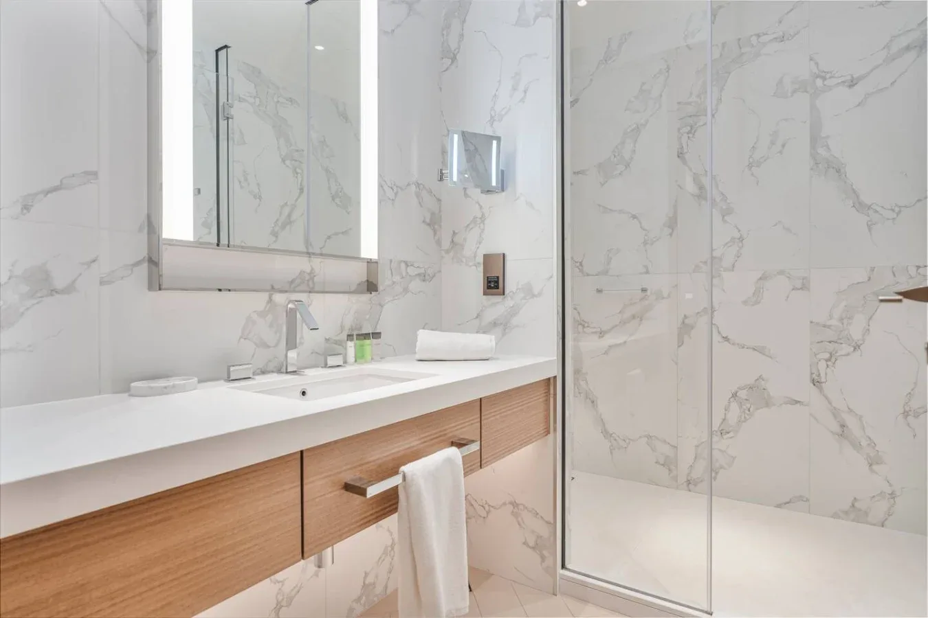 A bright bathroom with a wide sink vanity and a glass shower.