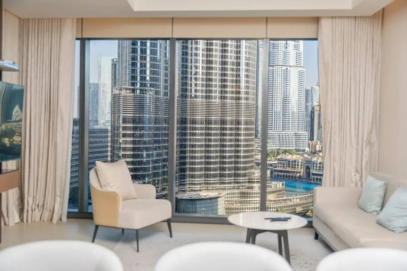 A bright living room with seating beside large windows overlooking city buildings.