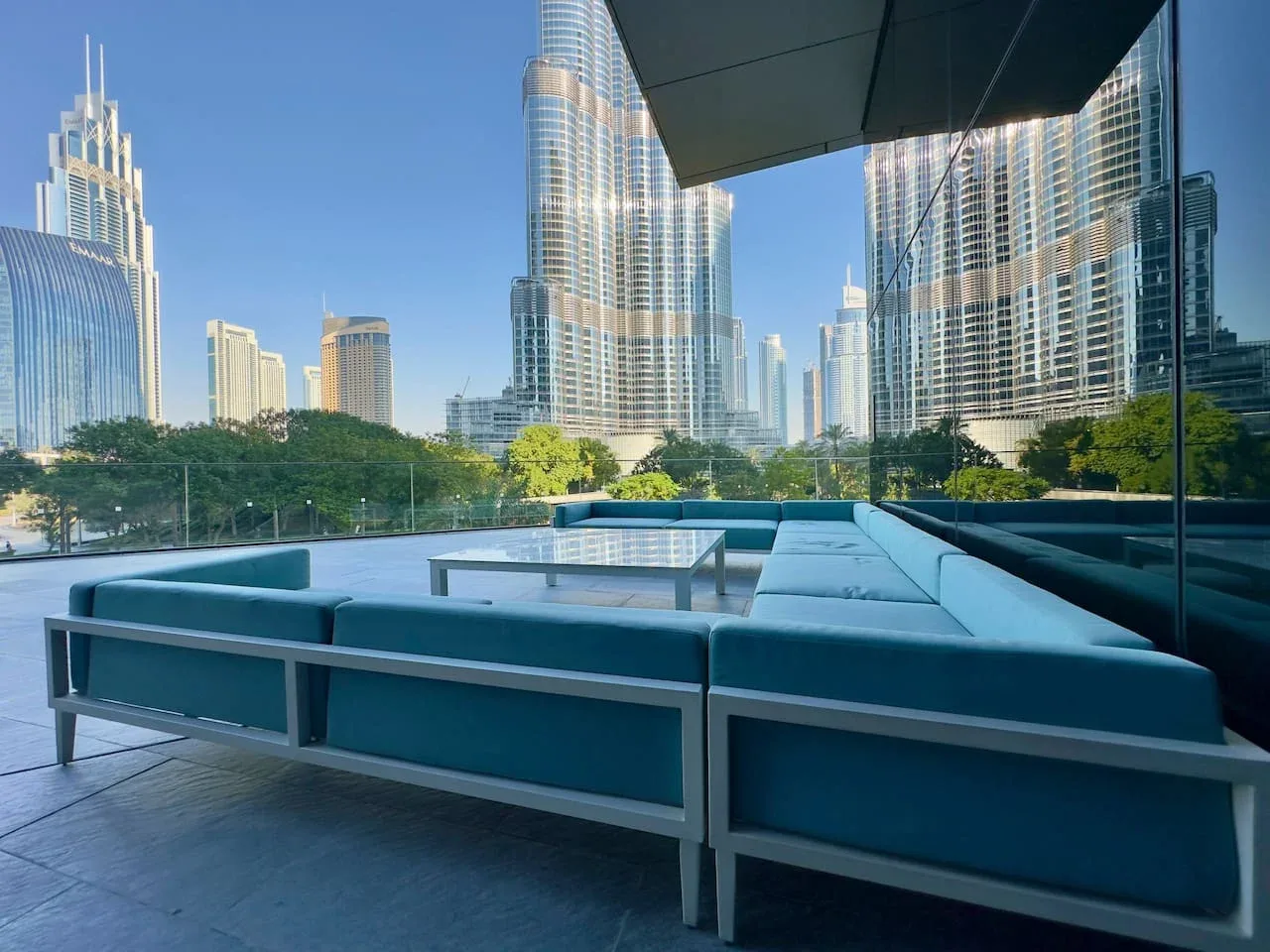 A rooftop terrace with blue seating overlooks a city skyline.