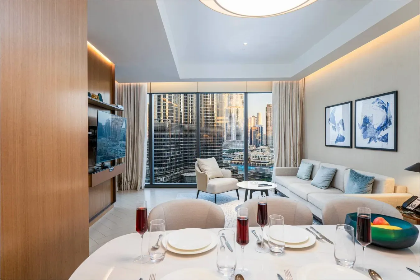 A modern living and dining area with large windows overlooking city buildings.