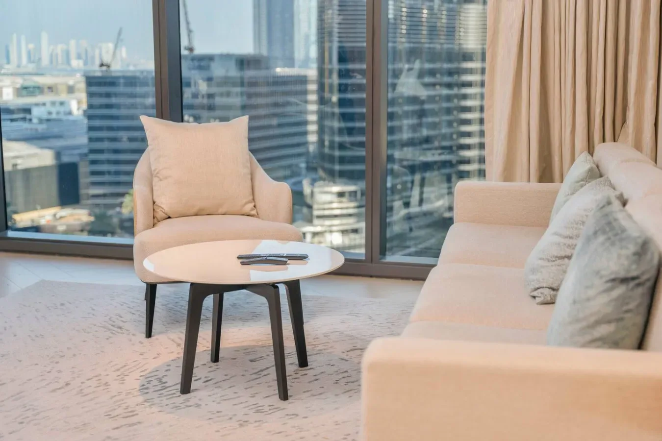 A bright living room seating area with a coffee table beside large windows.