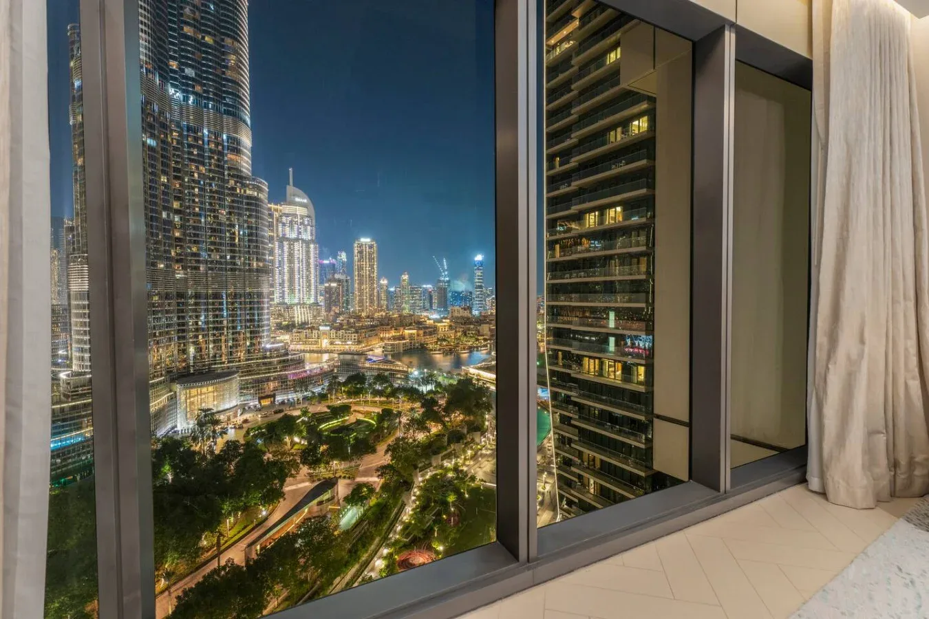 Floor-to-ceiling windows overlook a brightly lit city skyline at night.