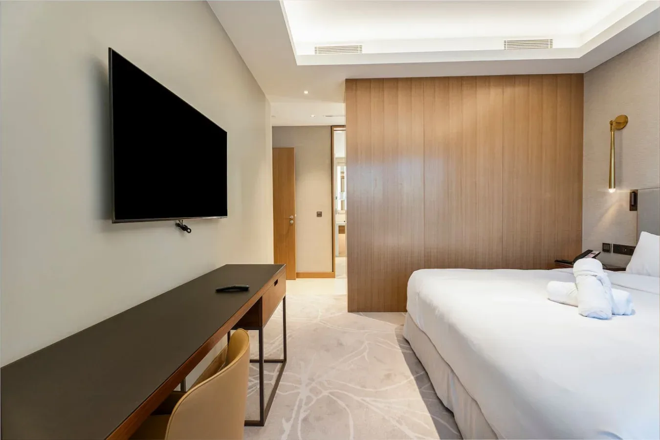 A bedroom with a bed, wall-mounted television, and wooden partition.