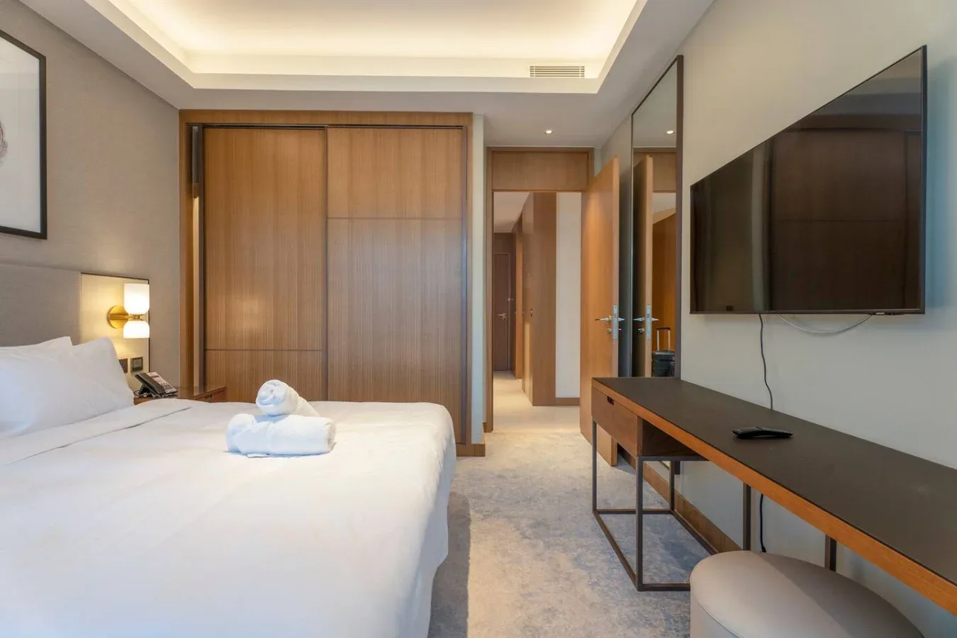 A bedroom with a bed, wooden wardrobe, and television.