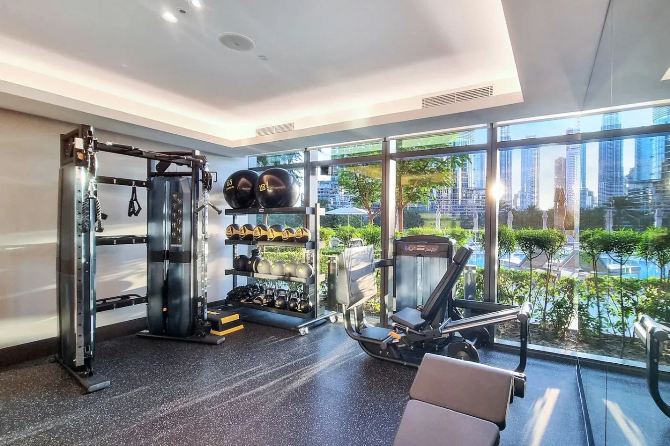 A gym with exercise equipment beside large windows overlooking the city.