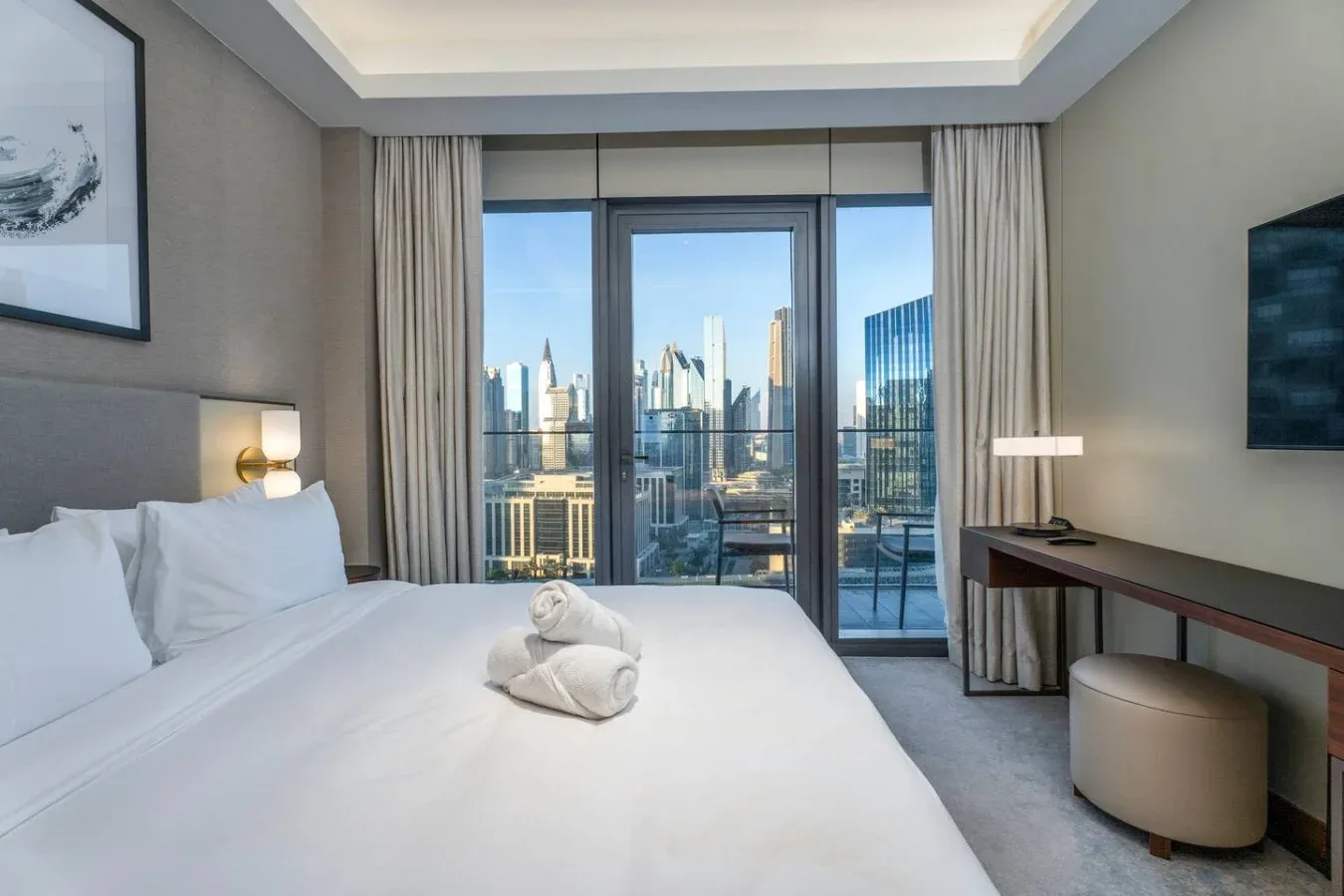 A bedroom with a large bed facing floor-to-ceiling windows overlooking the city.