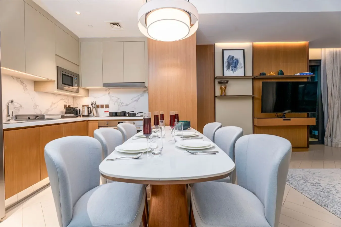 A dining area with a set table and kitchen counters beside a television.