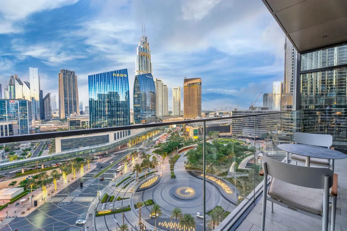 A balcony overlooks a city skyline and landscaped plaza.